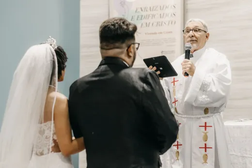 A priest officiates a wedding ceremony speak - Competitor Platforms