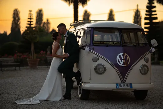 Newlyweds embrace by a vintage vw bus at sun - Marriage & Relationships